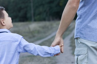 Mutlu çocuk ve ebeveynin parktaki gezinin doğasında elleri var.