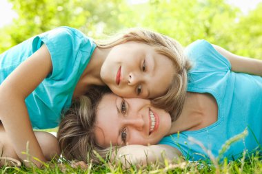 Anne ile çocuk parkta çimlerin üzerinde oynuyorlar.