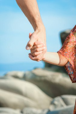 Deniz kenarındaki anne ve babanın güzel elleri.