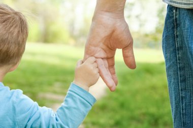 Mutlu bir geçmişi olan çocuğun elini tutan ebeveyn.