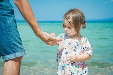 Mutlu ebeveyn ve çocuğun elleri Deniz Yunan arka planında