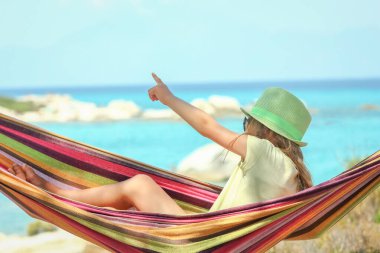 Yunan arka planında hamakta mutlu bir çocuk.