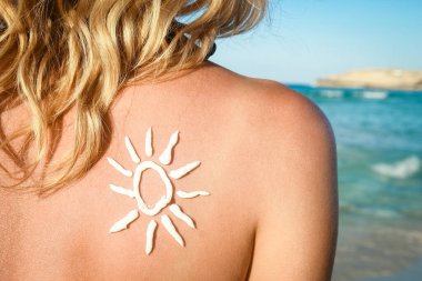 Sırtında güneş, doğada deniz kenarında mutlu bir kız.