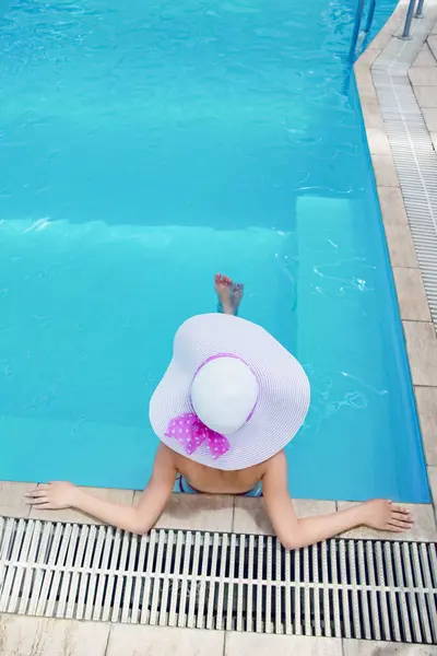 一个戴帽子的鼓风机躺在一个放松的游泳池里 在旅程中 免版税图库照片