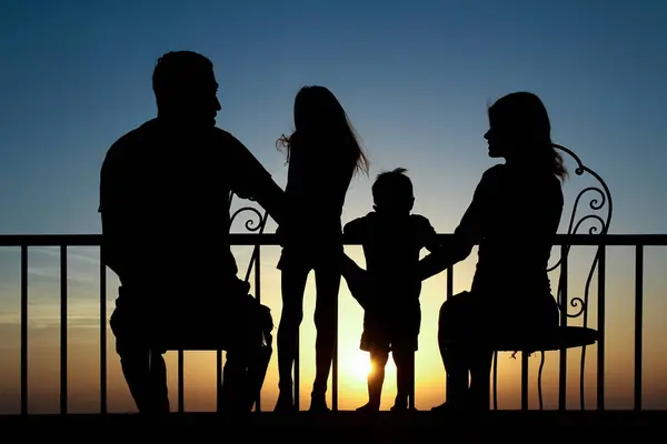 海のシルエットの背景の夜明けに幸せな家族 ストック写真