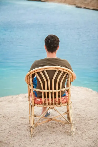 快乐的家伙坐在凳子上 在大自然的海背景 免版税图库图片