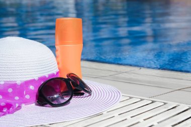 Havuzun yanında kremalı ve gözlüklü güzel bir şapka.