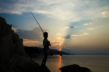 Deniz kenarında balık tutan mutlu çocuk.