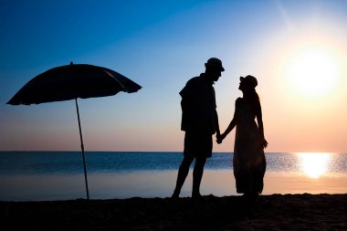 Gün batımında deniz kenarında mutlu bir çift doğada gezici bir siluette