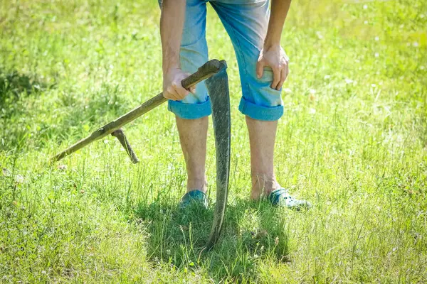 Stock image man mows grass with scythe gardening