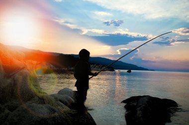 Deniz kenarında balık tutan mutlu çocuk.