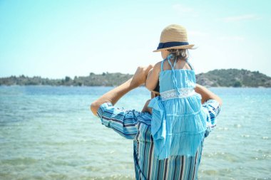 Çocuklu bir ebeveyn parkta, deniz yolculuğunun arka planında.