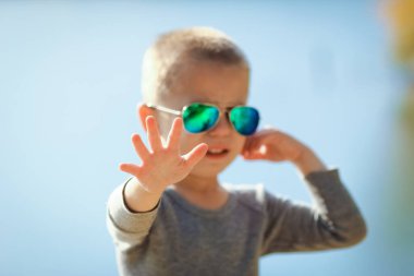 Güneş gözlüklü mutlu çocuk parkta doğada geziyor.