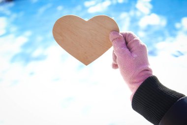 Doğadaki bir parkta Sevgililer Günü 'nde gökyüzüne karşı duran bir kızın ellerinde.
