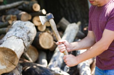 Baltalı ülke geçmişi olan bir adam odun kesiyor.