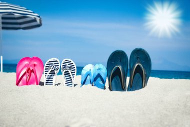 Plaj yaz tatili afişi. Parmak arası terlik ve şapkalı, üzerinde tahta ve top olan okyanus kıyısındaki kumda. Deniz kıyısında yaz aksesuarları. Tropik tatil ve rahat seyahat konsepti. Üst görünüm ve kopyalama alanı.