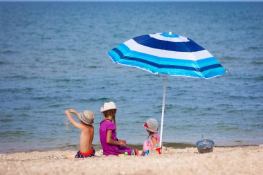 Şemsiye geçmişi olan, deniz kenarında oynayan mutlu çocuklar.