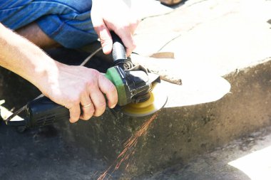 Bir adam öğütücüyle çalışır ve küreği biler.