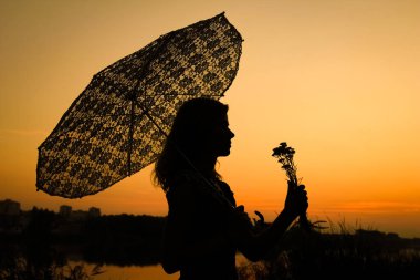 Parktaki günbatımında şemsiyeli mutlu kız.