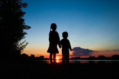 Mutlu çocuk siluetleri günbatımı arka plan üzerinde