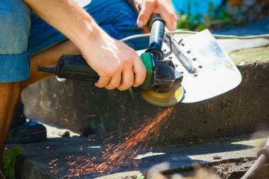 Bir adam öğütücüyle çalışır ve küreği biler.