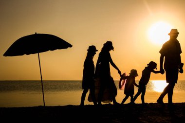 Gün batımında deniz kenarında mutlu bir aile doğada gezici bir siluette