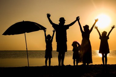 Gün batımında deniz kenarında mutlu bir aile doğada gezici bir siluette