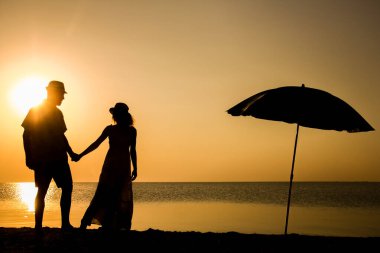 Gün batımında deniz kenarında mutlu bir çift doğada gezici bir siluette