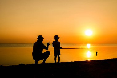 Mutlu baba ve çocuk balıkçılar deniz kenarında balık yakalar.