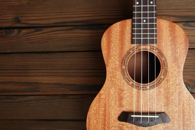 Kahverengi ahşap arka planda ukulele gitar