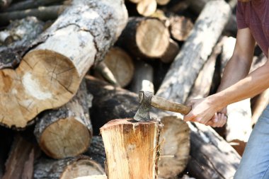 man chopping wood with an ax country background clipart