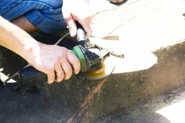 Bir adam öğütücüyle çalışır ve küreği biler.