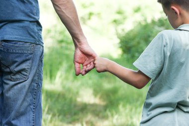 Baba ellerinin oğlunun elini tutması konseptini koruma ailesi.