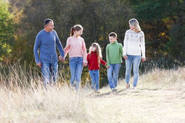 Mutlu aile sonbahar konseptiyle parkta birlikte yürüyor. Mutluluk.