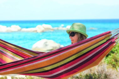 Yunan arka planında hamakta mutlu bir çocuk.