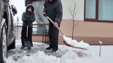 Mutlu bir baba ve oğlu kışın evin yakınındaki karları temizliyor.
