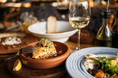 Restoranda bir bardak beyaz şarapla servis edilen Yunan yemeği. 