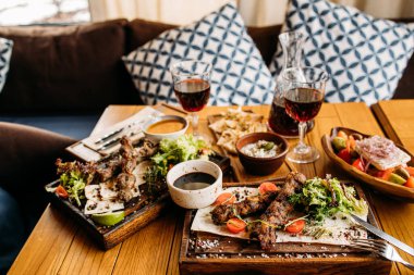 Restoranda ızgara barbekü eti, Yunan salatası ve kırmızı şarapla servis ediliyor. 