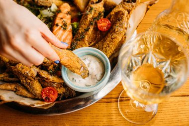 Kızarmış balığı sosa batırmak, beyaz şarapla servis edilen kızarmış balık tabağı.