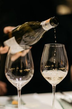 Sommelier barda bardağa köpüklü şarap dolduruyor.