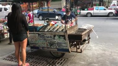 Pattaya 'da sokak yemeği. Genç bir Taylandlı kadın kömürde lezzetli balık pişirir. Tayland. Pattaya. 13.02.2018.
