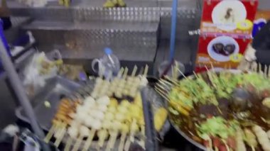 İnsanlar Pratunam gece pazarında bir sürü farklı giysi ve eşyanın satıldığı yerlerde dolaşıyorlar. Tayland, Bangkok, Pratunam pazarı. 03.17.2023.