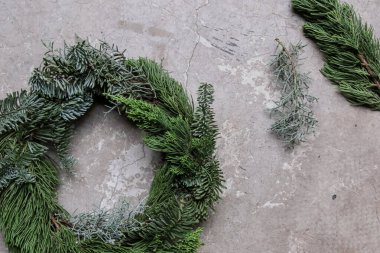 Gri arka planda taze çam dalı olan el yapımı Noel çelengi.