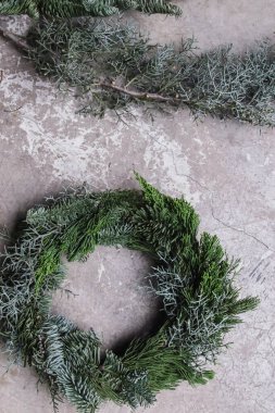 Gri arka planda taze çam dalı olan el yapımı Noel çelengi.