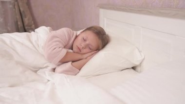 A long-haired girl in a gown is lying sidelong in the bed with her eyes closed and sleeping. The panning camera and it stops in the end
