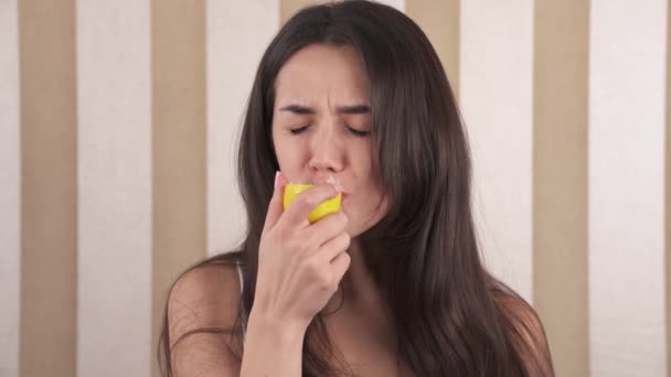 一个年轻的高加索女人的画像 这个女孩吃了个酸黄色的柠檬 脸都红了 — 图库视频影像
