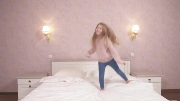 Μακρυμάλλικο Κορίτσι Πουλόβερ Και Τζιν Πηδάει Και Χορεύει Στο Κρεβάτι — Αρχείο Βίντεο