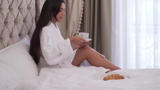 Uma Jovem Morena Vestido Branco Está Bebendo Café Sua Cama — Vídeo de Stock
