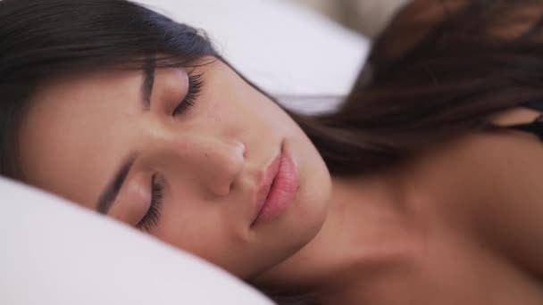 美しい若い女性の顔のクローズアップ 彼女は眠りから覚めている 彼女の髪は枕の上にある 右から左へカメラをパンニング — ストック動画