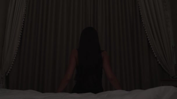 Long Haired Brunette Sits Bed Facing Closed Window Dark Room — Video Stock